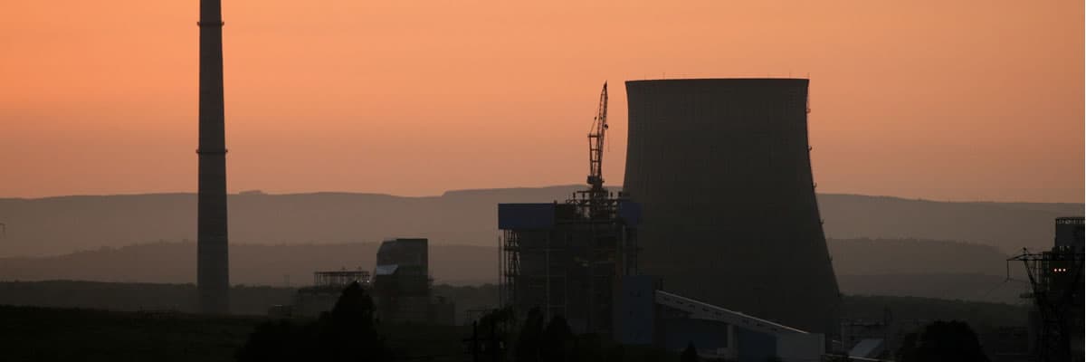 Silhueta da usina termelétrica de Candiota ao pôr do sol, com a torre de resfriamento e a chaminé